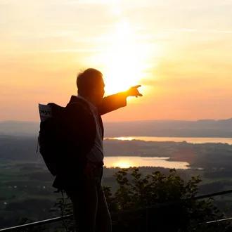 Psychotherapeut zeigt in der Abendsonne auf die weite Allgäuer Landschaft – inspirierendes Bild für psychotherapeutische Karrierewege in der Fachklinik Allgäu.