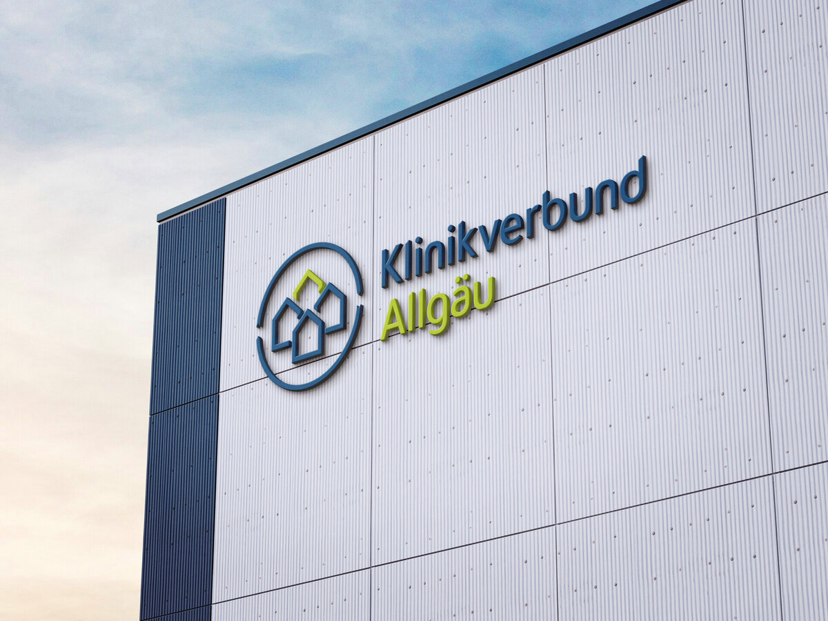Fassadenbeschriftung mit dem blau-grünen Logo des Klinikverbunds Allgäu