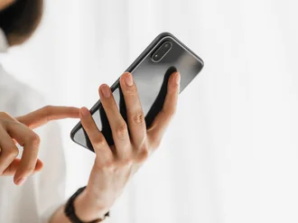 Nahaufnahme einer Person, die ein Smartphone in der Hand hält und mit dem Finger den Bildschirm berührt