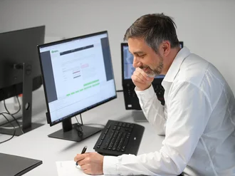 Webentwickler bei der Denkströme arbeitet konzentriert am Computer mit Code und Website-Entwurf auf dem Bildschirm