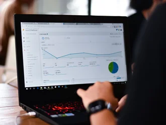 Person analysiert Website-Daten auf einem Laptop mit Google Analytics; sichtbare Diagramme, Statistiken und KPIs zur Performance-Messung