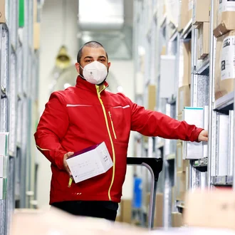 Mitarbeiter im Lager des DHZM bei der Kommissionierung medizinischer Produkte – effiziente Logistik im Gesundheitswesen mit Hygieneschutz.