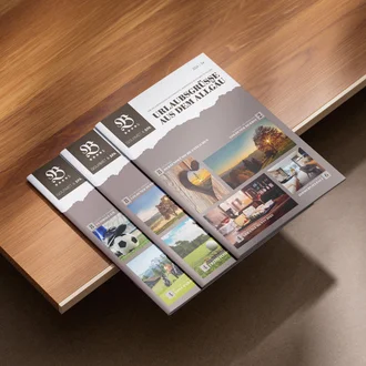 Drei Ausgaben des Urlaubsmagazins „Urlaubsgrüße aus dem Allgäu“ vom Parkhotel Burgmühle auf Holztisch, mit Titelseiten zu saisonalen Themen