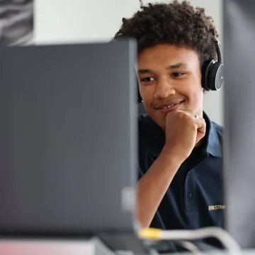 Denkströme Mitarbeiter mit Headset arbeitet konzentriert am Bildschirm im Büro – Szene aus der Website-Entwicklung und technischen Umsetzung.