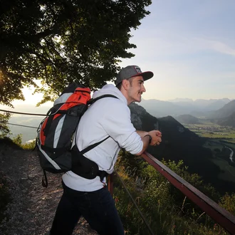 Motivierter junger Mann in Freizeitkleidung mit Wanderrucksack überblickt das Tal – visuelles Leitmotiv für den Berufseinstieg bei der Fachklinik Allgäu im Rahmen der Kampagne „Gemeinsam Berge überwinden“.