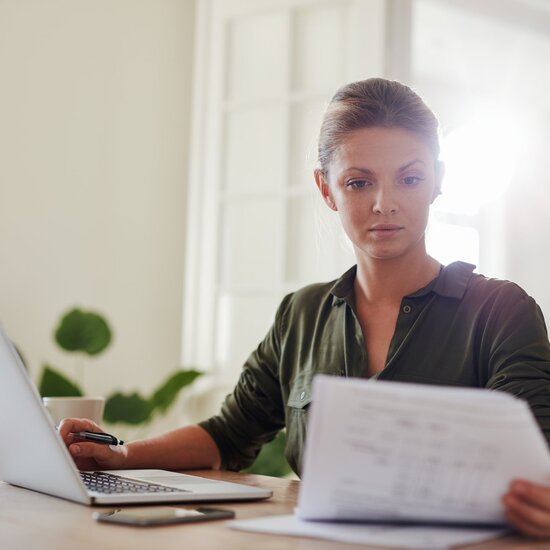 Junge Frau arbeitet fokussiert als Junior Consultant mit Laptop und Dokumenten – moderne Arbeitswelt und digitale Beratung