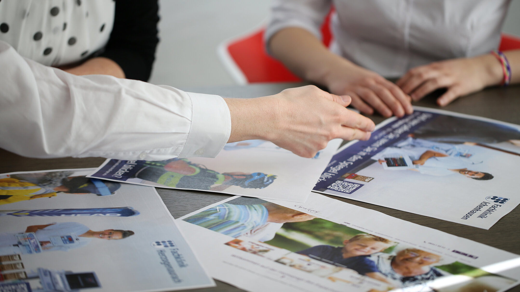 Denkströme Team diskutiert Personalmarketing Kampagne mit medizinischen Motiven am Tisch – kreative Konzeptentwicklung für Gesundheitskampagnen