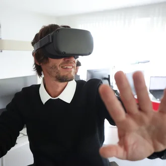 Mitarbeiter aus dem Technikteam von Denkströme testet eine VR-Brille im Büro und streckt die Hand nach vorn, als würde er virtuelle Elemente bedienen.