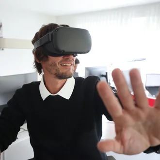 Mitarbeiter aus dem Technikteam von Denkströme testet eine VR-Brille im Büro und streckt die Hand nach vorn, als würde er virtuelle Elemente bedienen.