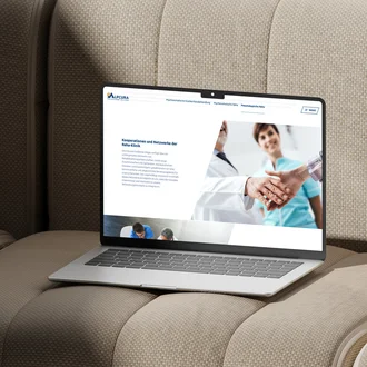Laptop auf beigem Polstermöbel zeigt Website der Alpcura Fachklinik Allgäu mit Informationen zu Kooperationen und Netzwerken im Gesundheitsbereich.