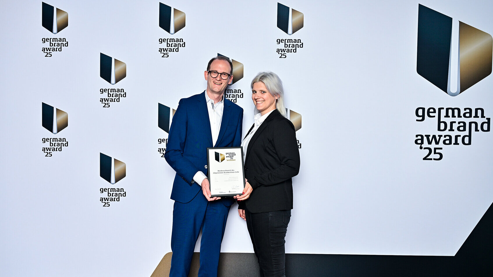 Fabian und Teresa Schmid, Geschäftsführer der Kommunikationsagentur Denkströme, bei der Verleihung des German Brand Award 2025 in Berlin. Beide halten eine Urkunde vor der offiziellen Award-Wand und lächeln in die Kamera. Die Preisverleihung würdigt exzellente Markenführung in Europa und fand im Rahmen der renommierten German Brand Convention statt.