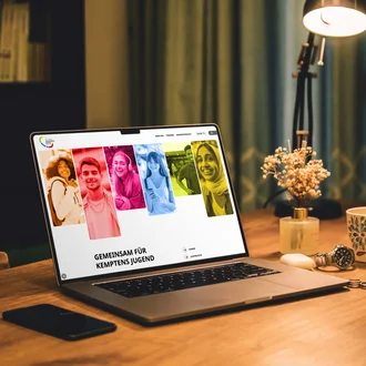 Mockup Laptop mit der Website des Stadtjugendrings Kempten auf einem Holztisch.