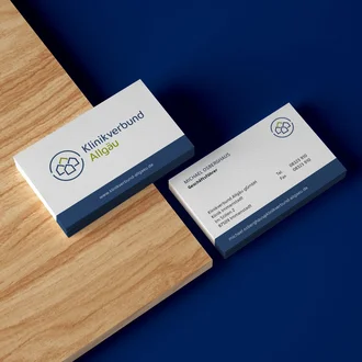 Geschäftliche Visitenkarten des Klinikverbunds Allgäu mit Logo, Kontaktdaten und blauem Gestaltungselement