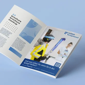 Aufgeschlagene A4-Recruiting-Broschüre mit Klinikdesign auf hellem Hintergrund, rechte Seite zeigt Mitarbeiterin der Fachklinik Herzogenaurach im Gespräch mit Patientin in Sportjacke und Skibrille.