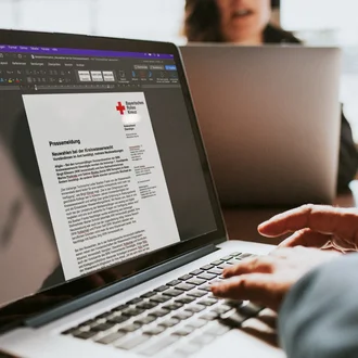 Laptop mit geöffneter Word-Datei einer Pressemitteilung des Bayerischen Roten Kreuzes zur Neuwahl der Kreiswasserwacht – professionelle Öffentlichkeitsarbeit und digitale Textverarbeitung im Einsatz