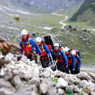 Bergretterinnen und Bergretter der Bergwacht im Einsatz: Team mit Trage in alpinem Gelände auf Rettungsmission – ausdrucksstarke Szene ehrenamtlicher Notfallhilfe in den Bergen