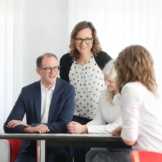 Fröhliches Teammeeting bei der Denkströme mit Fokus auf Zusammenarbeit und moderner Unternehmenskultur