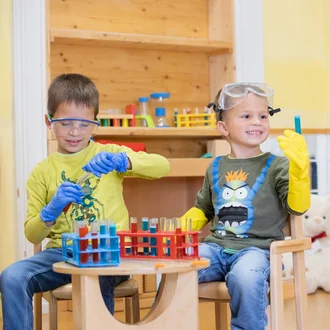 Zwei Kinder im Rollenspiel als Laboranten mit Schutzbrillen, Gummihandschuhen und Reagenzgläsern – lebendiges Kampagnenmotiv für die Ausbildung zur/zum Medizinisch-Technischen Laboratoriumsassistent*in (MTLA) beim Klinikverbund Allgäu.