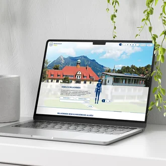 Startseite des Klinikverbund Allgäu auf einem Laptop mit interaktivem Körperkompass vor Alpenkulisse; digitale Orientierungshilfe zu Fachbereichen und Standorten der Klinik auf modernem Webinterface.
