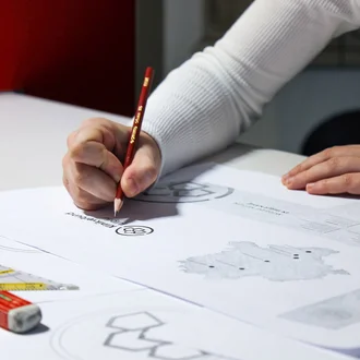 Handskizze des Logos für den Klinikverbund Allgäu mit rotem Bleistift während der Markenentwicklung