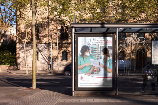 Bushaltestellenplakat des Deutschen Herzzentrums München mit Pflegekräften auf der Intensivstation – Recruiting-Kampagne „Kleine und große Herzensangelegenheiten“ für medizinisches Fachpersonal