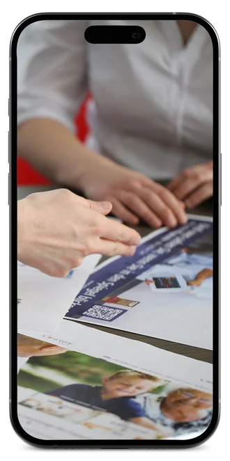Bild in einem Smartphone: Denkströme Team diskutiert Personalmarketing Kampagne mit medizinischen Motiven am Tisch – kreative Konzeptentwicklung für Gesundheitskampagnen