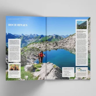 Aufgeschlagenes Bergjournal mit Wandertipps, Panoramablick auf Allgäuer Alpen und türkisfarbenem Bergsee bei Sonnenschein