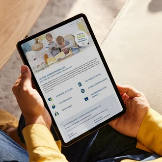 Person hält Tablet mit geöffneter Infoseite zu den digitalen Ausbildungswochen des Klinikverbunds Allgäu mit Vorteilen für Azubis und Kinderbild im Header.