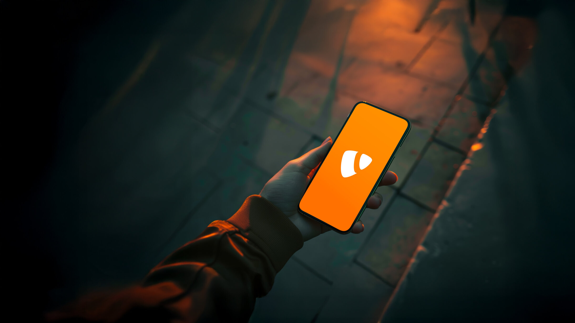 Hand hält Smartphone mit orangefarbenem Bildschirm und TYPO3-Logo, fotografiert bei Dämmerlicht auf dunklem Gehweg – symbolisiert Content-Management, Webentwicklung und mobile CMS-Nutzung