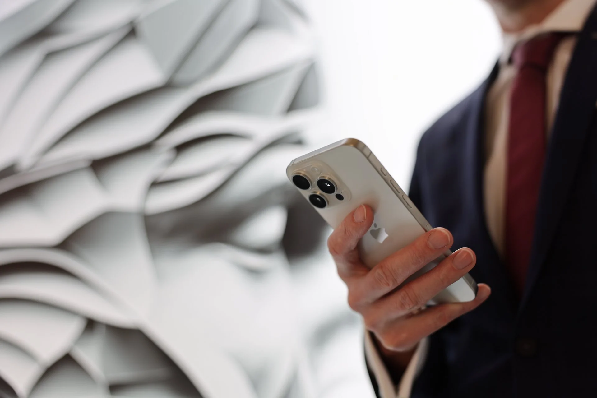 Business-Person im Anzug hält ein modernes iPhone – Fokus auf digitale Kommunikation, mobile Technologie und professionellen Arbeitsalltag