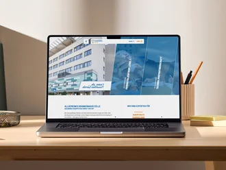 Laptop auf Schreibtisch mit geöffneter Website des Allgemeinen Krankenhauses Celle, Startseite mit Klinikfoto und Navigationselementen sichtbar