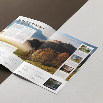 Aufgeschlagenes Reisejournal mit herbstlicher Allgäu-Landschaft, Angeboten und Tipps für Wellness- und Aktivurlaub