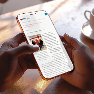 Person liest auf Smartphone eine Nachrichtenseite des Bayerischen Roten Kreuzes über turnusmäßige Neuwahlen beim Jugendrotkreuz – digitale Kommunikation und Engagement im Ehrenamt