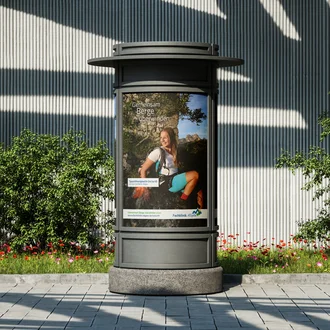 Sporttherapeutin auf einer Wanderung in den Bergen – authentisches Werbemotiv der Fachklinik Allgäu auf einer Litfaßsäule im urbanen Raum, Teil der emotionalen Recruiting-Kampagne.