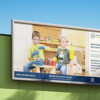 Großflächenplakat mit zwei Kindern beim Labor-Rollenspiel in Schutzbrillen – aufmerksamkeitsstarkes Motiv für die Ausbildung zur/zum medizinisch-technischen Laboratoriumsassistent:in im Klinikverbund Allgäu.