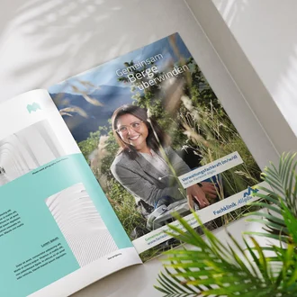 Aufgeschlagene Broschüre mit Recruiting-Anzeige der Fachklinik Allgäu „Gemeinsam Berge überwinden“ neben Projektvorstellung in hellem Setting mit Pflanzen.