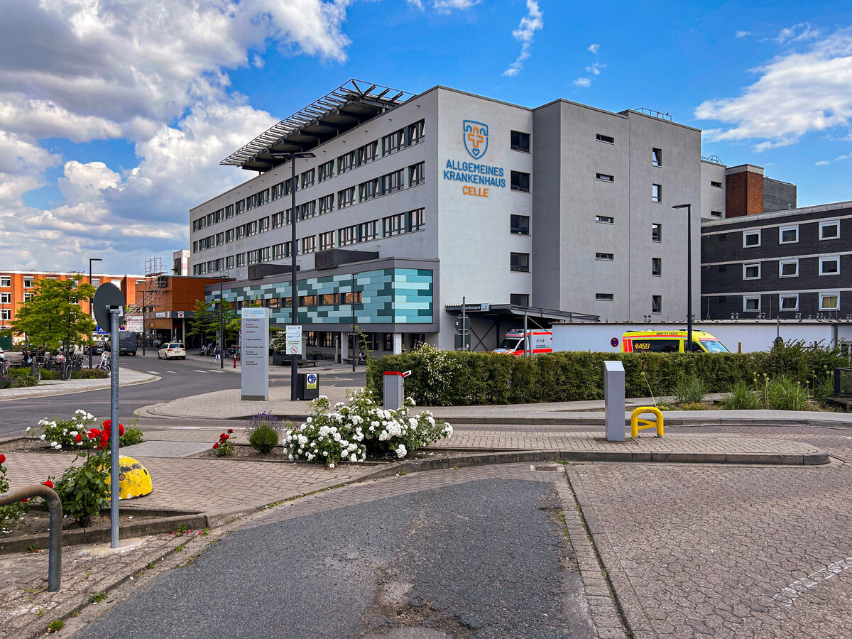 Außenansicht des Allgemeinen Krankenhauses Celle mit neuer Fassadengestaltung, Logo an der Wand und Rettungswagen im Einsatzbereich