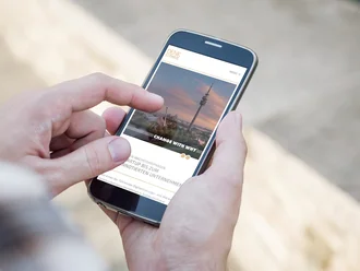 Person nutzt Smartphone mit geöffneter Denkströme-Website – responsives TYPO3-Webdesign für Digitalagentur mit Fokus auf Change-Kommunikation und Markenstrategie