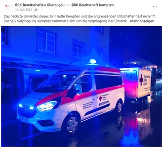 Rettungsfahrzeug und Verpflegungsanhänger des BRK Kempten im nächtlichen Einsatz bei Unwetter – Blaulichtreflexionen auf nasser Straße, SEG Verpflegung sorgt für Versorgung der Einsatzkräfte in Kempten und Umgebung