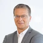 Business-Porträt von Andreas Ruland im grauen Anzug mit verschränkten Armen – zufriedener Unternehmensvertreter 