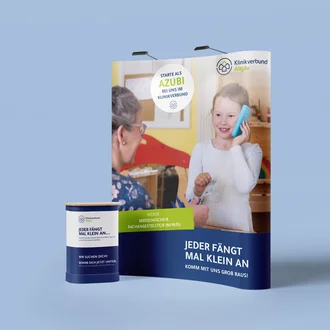 Messe-Display mit lächelndem Kind am Spieltelefon in Arztpraxis-Kulisse – werbewirksamer Auftritt des Klinikverbund Allgäu zur Gewinnung von Fachangestellten im Gesundheitswesen.